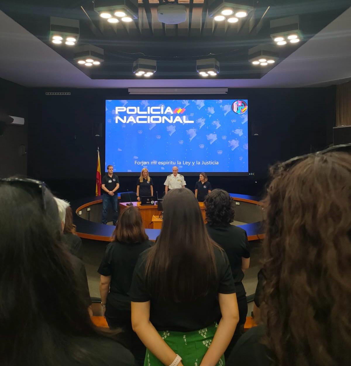 Equipo de Cyberwoman posando frente a la presentacion de la policía nacional